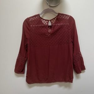 Women’s three quarter sleeve, loose fit maroon top.